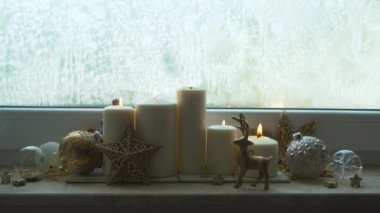 Genişliğinde noel süslemeleri olan beyaz yanan mumlar