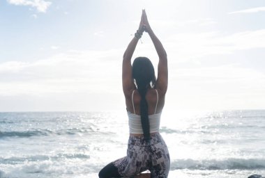 Yaşam dengesi. Sporda tam boy zayıf sporcu kadın ağaç duruşu ya da vrikshasana yaparken sakin bir sabahta deniz kenarında yoga ve meditasyon yaparken, dikiz aynasından giyiniyor. Sağlıklı yaşam tarzı kavramı