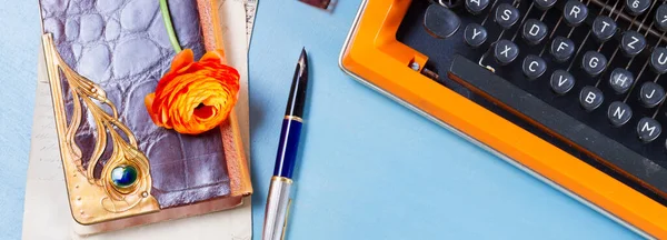 带橙色复古打字机和老式笔记本的工作区 在蓝桌背景上复制空间 — 图库照片