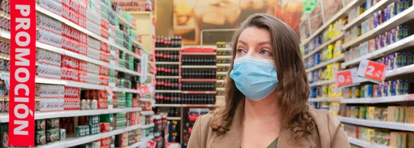 Woman wearing protecting mask with shopping cart close up, checking product description, shopping during pandemia and coronavirus oubreak