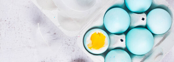 Set of blue easter eggs, one with yolk, top view on wooden aged table