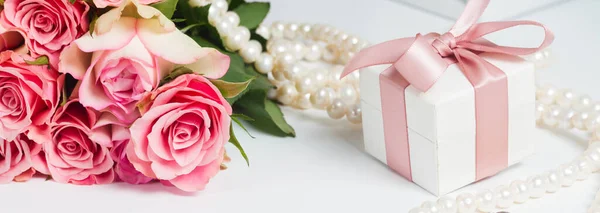 礼品盒粉红色丝带与珠宝和浪漫玫瑰在白色的桌子上 — 图库照片