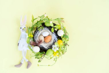 Yuvada renkli yumurtalar ve el yapımı tavşanlı Paskalya sahnesi.