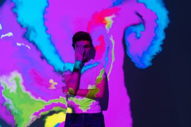 Etkileşimli sanal video kurulumuna sahip yetenekli yenilikçi çocuk. Yeni sanat formu, üretken grafikler. Genç adamın silueti sanal gerçeklikte dijital sanatı resmediyor