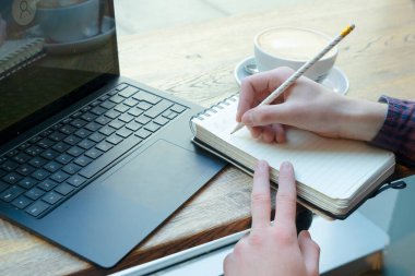 Boy student writting in notebook homework or social media communicating. hands with keyboard close up
