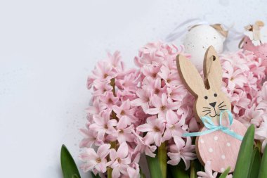 Paskalya sahnesinde taze pembe sümbül çiçekleri ve yumurtalı Paskalya Tavşanı.