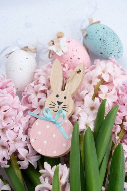 Paskalya sahnesinde taze sümbül çiçekleri ve yumurtalı Paskalya Tavşanı.