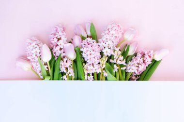 Easter scene with fresh tulips and hyacinth flowers border over pink background, copy space
