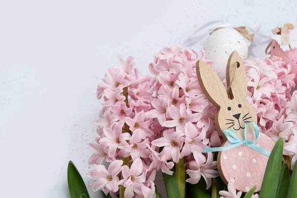Paskalya sahnesinde taze pembe sümbül çiçekleri ve yumurtalı Paskalya Tavşanı.