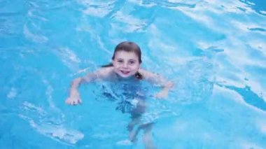 Small happy boy swimming in blue pool