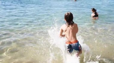 Small happy boy running and swimming in sea watr at resort