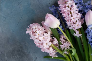 Paskalya sahnesinde taze laleler ve sümbül çiçekleri gri arka planda.