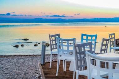 seaside cafe tables near beach at sunset, Corfu Greece