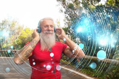 Beyaz sakallı kıdemli atlet dışarıda koşuyor, kulaklıkla müzik dinliyor.