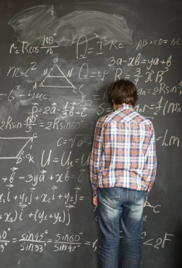 Teenageer çocuk, blackboard duran ve karmaşık matematik formülleri ile sorun yaşıyorsanız