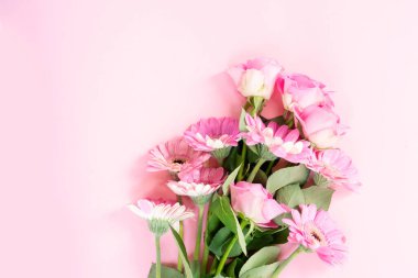 düğün ya da anneler günü geçmişi, pembe arka planda bir buket gül ve herberalar.