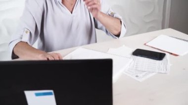 Modern dizüstü bilgisayarla çalışan ve faturalarını, teknolojisini ve yaşlılar yaşam tarzını kontrol eden yaşlı bir kadın.