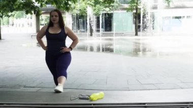 Woman and sports, exercise for weight loss in the fresh air. Happy curvy 40s woman doing workout stretch routine outdoor at city park