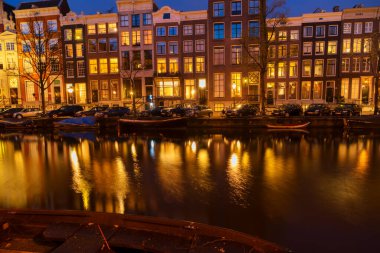 Tipik Hollanda evleri ile ışıklı windows yansımaları ile kanal üzerinde gece, Amsterdam, Hollanda