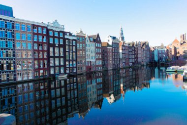 Amsterdam manzaralı Damrak kanalı tipik Hollandalı evleri ve botları ile bahar sabahı mavi saatte Hollanda, Hollanda.