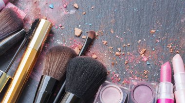 Siyah arkaplanda kopya alanı olan fırçalar, rujlar ve göz gölgeleri