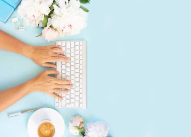 Düz yatıyordu ev ofis çalışma alanı çerçeve kopya alanı mavi zemin üzerine beyaz modern klavye, notebook ve şakayık çiçekleri yazarak someones el ile