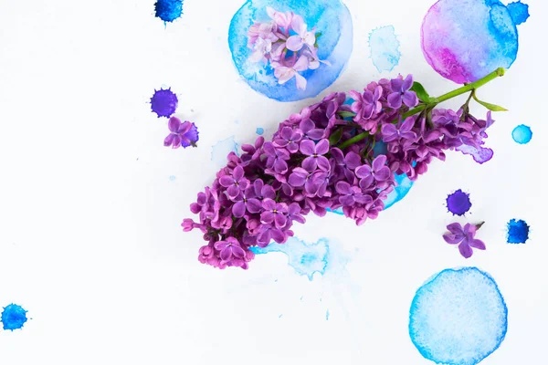Fresh lilac flowers frame over white background with watercolor paint splashes, flat lay flower composition with copy space