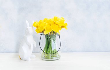 Paskalya yumurtası avı, paskalya tavşanı ve vazoda nergisler.