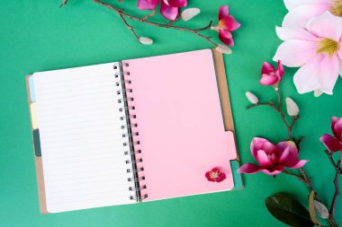 Yeşil zemin üzerinde çiçekler olan pembe manolya ağacı dalı, kopyalama alanı için defter sayfası aç