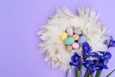 Paskalya sahnesinde menekşe arka planında renkli yumurtalar