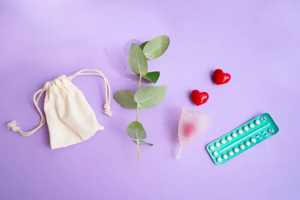 stock image Menstrual cup and pack of contraceptive pills over violet background, eco friendly and zero waste solution