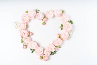 Çiçek kompozisyonu. Beyaz arka planda pembe gül çiçeklerinden yapılmış kalp çerçevesi. Düz konum, üst görünüm, kopyalama alanı
