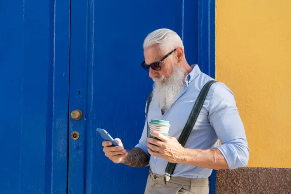 Senior hipster man with coffee and a phone, happiness, technology and elderly lifestyle people concept