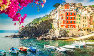 Riomaggiore picturesque town with moored boats of Cinque Terre with flowers, Italy