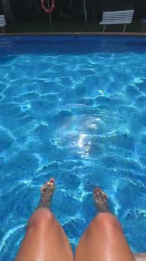 Clear water with ripples in tiled pool and someones legs