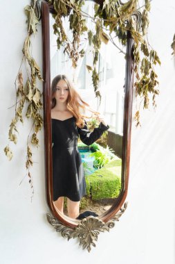 Büyüleyici bir ayna yansıması. Büyüleyici siyah elbiseli bir kadın. Güzel doğayla çevrili.