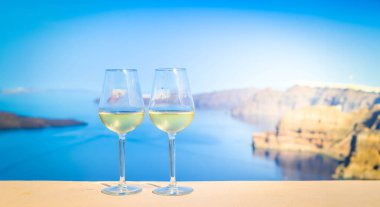 Arka planda Aegaen denizi olan iki bardak beyaz şarap, Yunanistan