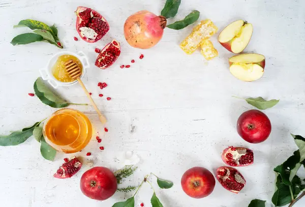 rosh hashana holiday - honey with apple and pomergranate over white desk background, top view frame with copy space