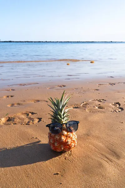 Stock image pinapple on a beach in sunglasses and headphones