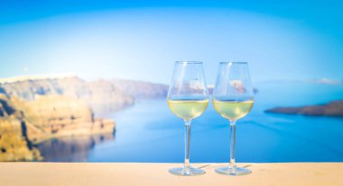 Arka planda Aegaen denizi olan iki bardak beyaz şarap, Yunanistan