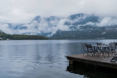 Büyüleyici dağlar ve yukarıdaki hafif sisli bulutlar arasında pitoresk bir Hallstatt gölü, Avusturya