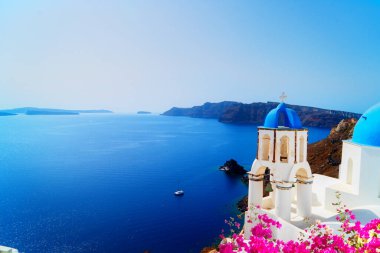 Yunanistan 'ın deniz ve kalderasına karşı mavi kubbeli ve beyaz duvarlı geleneksel Yunan köyü Oia of Santorini