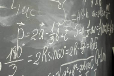 Kara tahta arka plan üzerinde beyaz tebeşir yazılı matematik formülleri ile