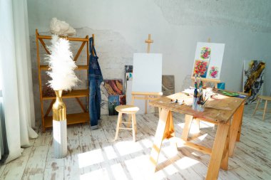 Bu parlak sanat stüdyosunda büyük bir masa, rahat bir sandalye ve yaratıcılığı teşvik eden renkli sanat eserleri bulunur.