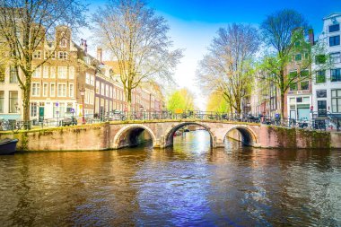 Eski tarihi evlerin cepheleri ve kanal suyu üzerindeki geleneksel köprü, Amsterdam, Hollanda