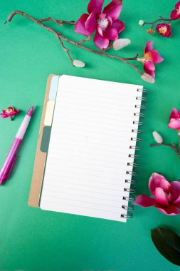 Yeşil zemin üzerinde çiçekler olan pembe manolya ağacı dalı, kopyalama alanı için defter sayfası aç