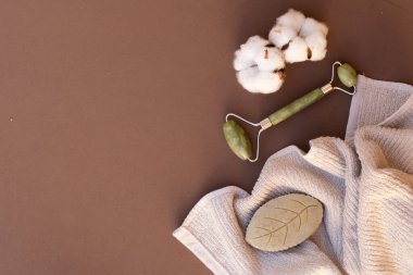 Gua sha, doğal taştan yapılmış yüz masajı silindiri, spa konsepti, yılın rengi, 2025 mocha mus.