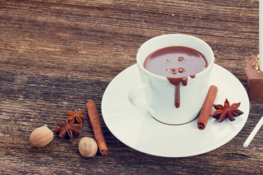 Beyaz bardakta sıcak çikolata ve ahşap masada marşmelov, 2025 yılının mocha mus rengi.