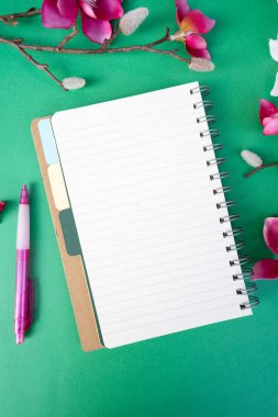 Yeşil zemin üzerinde çiçekler olan pembe manolya ağacı dalı, kopyalama alanı için defter sayfası aç