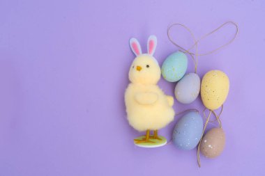 Paskalya sahnesinde menekşe arkaplan üzerinde renkli yumurtalar, kopyalama alanı
